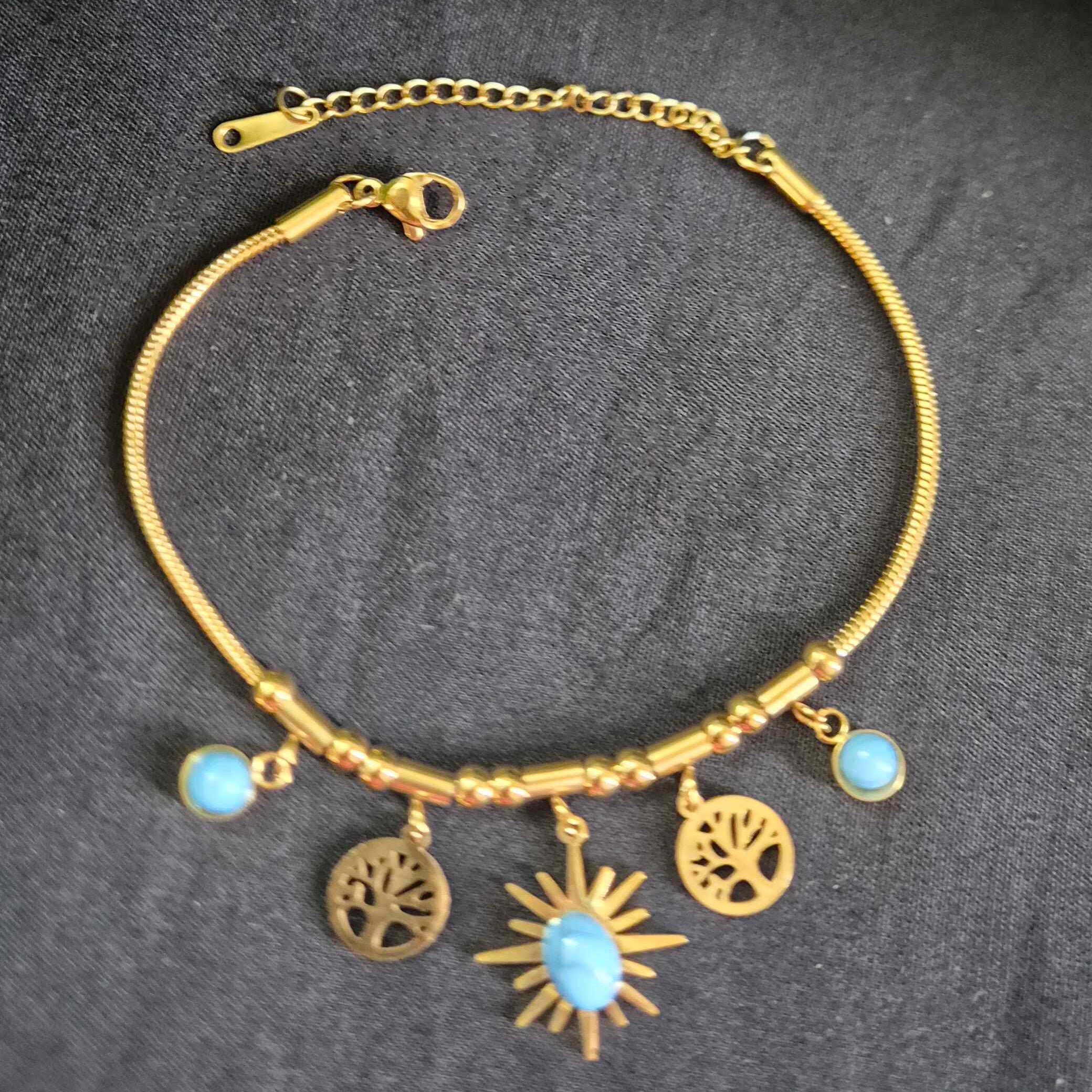 Gold-Tone Charm Bracelet with Blue Stone and Sunburst Pendant
